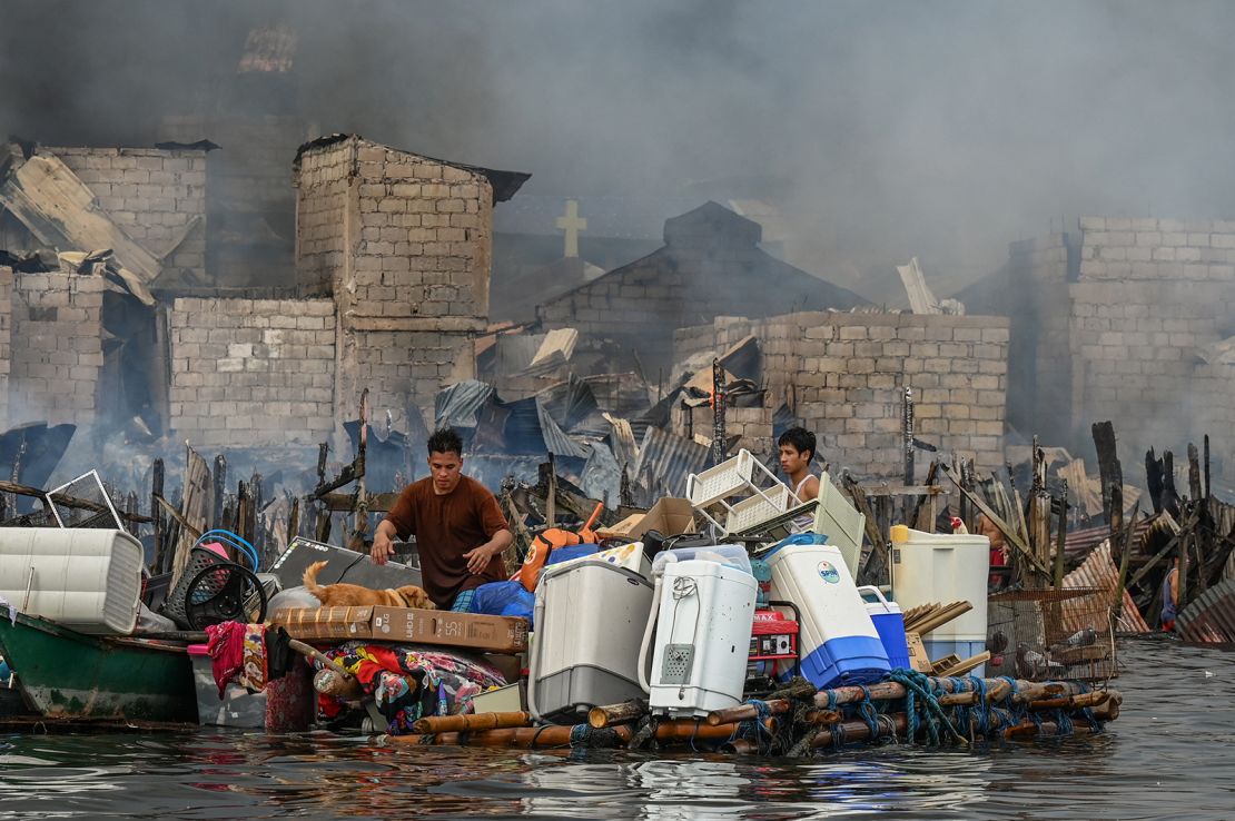 People carry their belongings on a makeshift raft during a fire in Tondo, Manila on November 24, 2024.