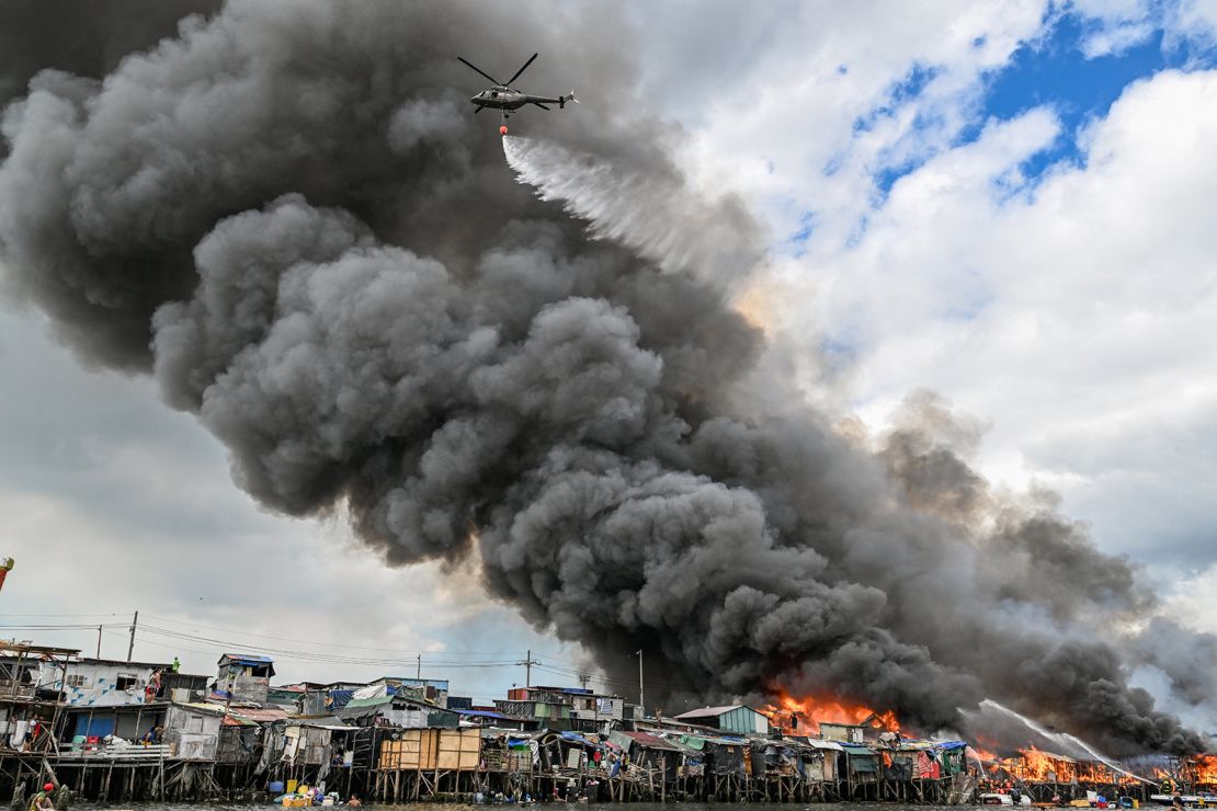 A Philippine Air Force helicopter drops water over shanty settlements ablaze in Tondo, Manila on November 24, 2024.