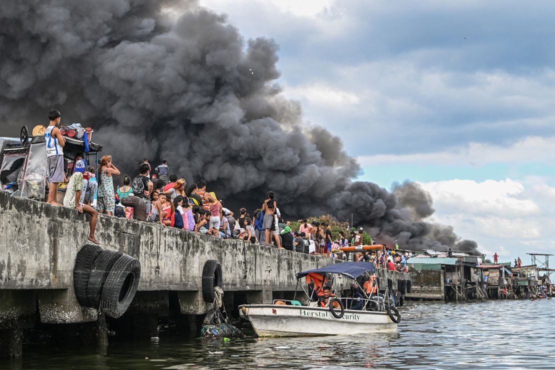 People watch houses on fire in Tondo, Manila on November 24, 2024.