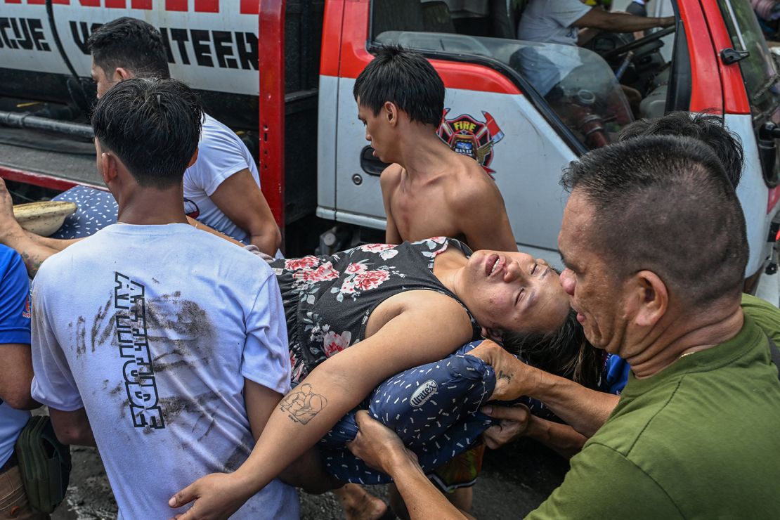 People carry a woman who fainted during the fire in Tondo, Manila on November 24, 2024.