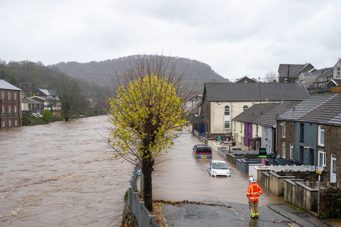 People pour water out of the front garden of properties on Sion Street in Pontypridd, Wales on November 24, 2024.