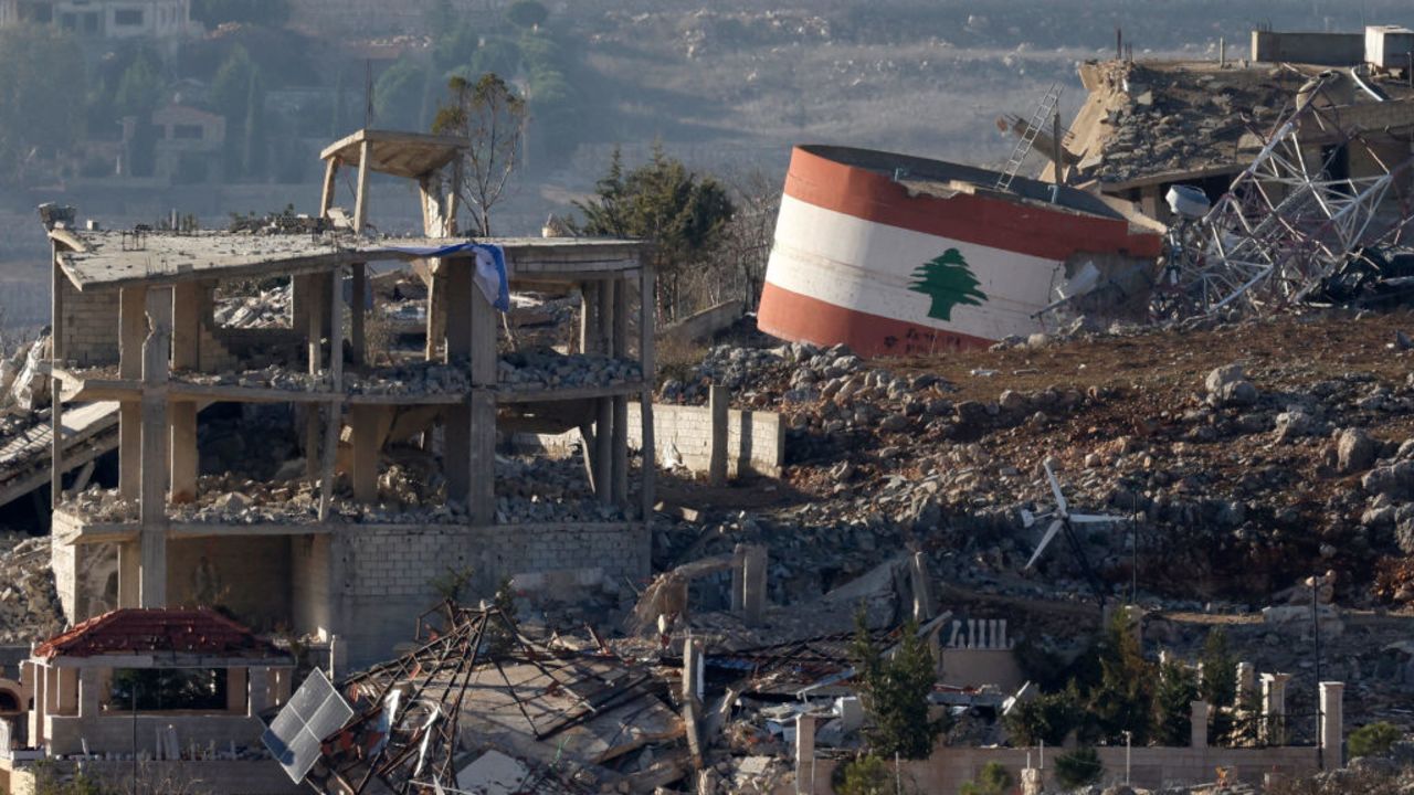 TOPSHOT - This picture taken from a position in northern Israel, near the border with Lebanon, shows an Israeli flag (L) on a destroyed building, and a Lebanese flag (R) painted on a damaged building in the southern Lebanese village of Meiss El-Jabal on November 25, 2024, amid the ongoing war between Israel and Hezbollah. Israeli ground forces have entered several villages and towns near Lebanon's southern border, including Khiam, where the Lebanese National News Agency (NNA) on November 25 reported clashes with Hezbollah fighters. In Mais al-Jabal, more than 1,000 buildings have been hit, according to the mayor of the village which counted some 30,000 residents before the conflict. (Photo by Jalaa MAREY / AFP) (Photo by JALAA MAREY/AFP via Getty Images)