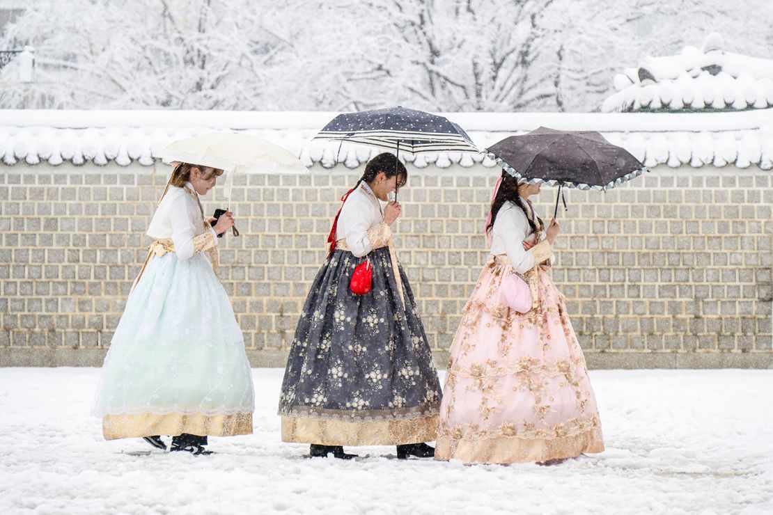 Visitors wearing traditional hanbok dresses are seen on the grounds of Gyeongbokgung Palace amid heavy snowfall in Seoul.