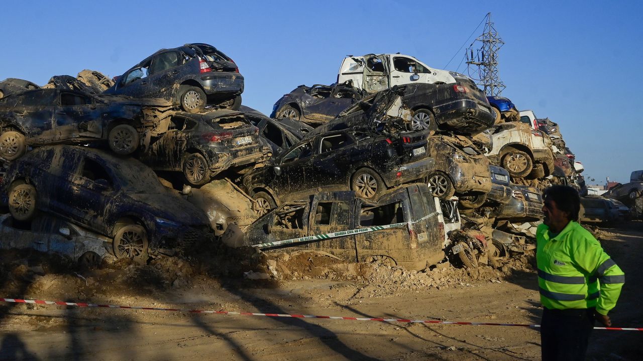 A security guard patrols near flood damaged cars in the aftermath of deadly flooding in Paiporta, near Valencia, eastern Spain, on November 27, 2024. There are no longer piles of mud in the streets but life has been at a standstill for many in this suburb of Valencia, Spain's third largest city, since torrential rains fell on October 29, killing at least 230 people mainly in the east of the country, including 45 in Paiporta. (Photo by JOSE JORDAN / AFP) (Photo by JOSE JORDAN/AFP via Getty Images)