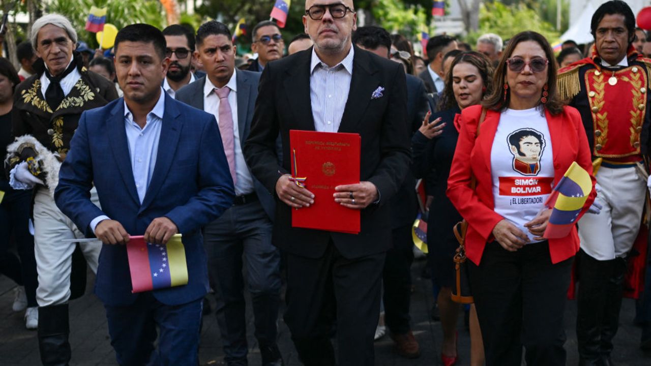 National Assembly President Jorge Rodriguez (C) walks as he holds a document of a bill passed by lawmakers that codifies economic sanctions as a crime against humanity and allows for the prosecution of anyone who expresses support for the measures in Caracas on 28 November 2024. Venezuela's parliament, controlled by the ruling Chavismo party, approved a law on Thursday that punishes with 25 to 30 years in prison the support of international sanctions against the country, in addition to establishing 60-year disqualifications for leaders who support them. (Photo by Juan BARRETO / AFP) (Photo by JUAN BARRETO/AFP via Getty Images)