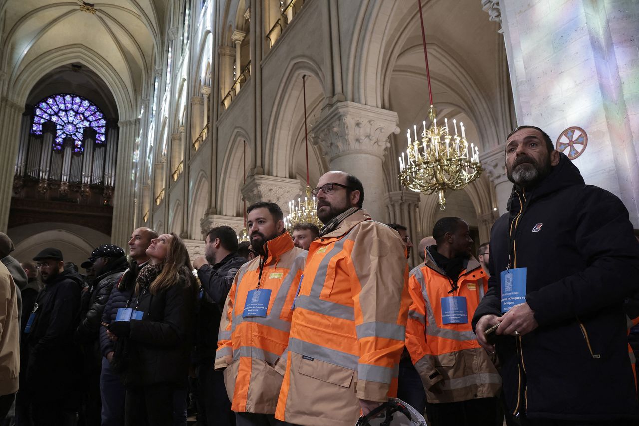 Construction workers who rebuilt the Notre Dame cathedral wait inside during a visit by French president.