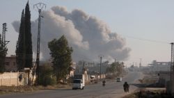 Fighters enter the Rashidin district on the outskirts of Aleppo on their motorbikes with smoke billowing in the background during fighting on November 29, 2024, as Hayat Tahrir al-Sham (HTS) jihadists and allied factions continue their offensive in the Aleppo province against government forces. The jihadists along with Turkey-backed factions launched this week a shock offensive against Syrian regime troops and sparked the deadliest battle the country has seen in years, with the violence killing so far 242 people, according to the Syrian Observatory for Human Rights. The war monitor said most of the victims were combatants on both sides but also including civilians. (Photo by Bakr ALKASEM / AFP) (Photo by BAKR ALKASEM/AFP via Getty Images)