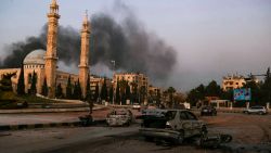 Smoke billows in the distance as damaged cars are seen at the site of Syrian regime airstrikes targeting anti-regime fighters in Aleppo, in Syria's northwestern Idlib province on November 30, 2024. Jihadists and their Turkish-backed allies breached Syria's second city of Aleppo on November 29, as they pressed a lightning offensive against forces of the Iranian- and Russian-backed government. (Photo by AAREF WATAD / AFP) (Photo by AAREF WATAD/AFP via Getty Images)