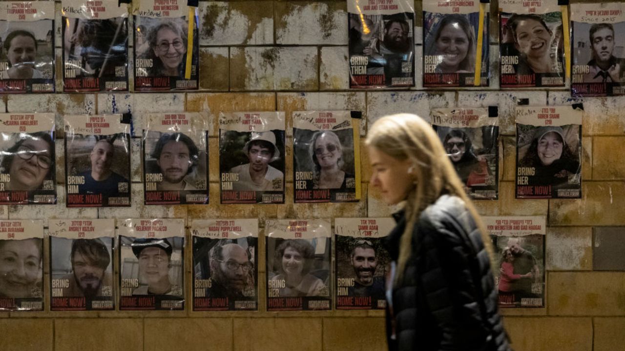 TEL AVIV, ISRAEL - NOVEMBER 30: A woman walks by a wall covered with photos of hostages held in Gaza Strip on November 30, 2024 in Tel Aviv, Israel. After the Lebanon cease-fire, the families of Israeli hostages are hoping for a hostage deal, with reports that the Hamas delegation is expected in Cairo for hostages deal talks. (Photo by Amir Levy/Getty Images)