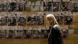 TEL AVIV, ISRAEL - NOVEMBER 30: A woman walks by a wall covered with photos of hostages held in Gaza Strip on November 30, 2024 in Tel Aviv, Israel. After the Lebanon cease-fire, the families of Israeli hostages are hoping for a hostage deal, with reports that the Hamas delegation is expected in Cairo for hostages deal talks. (Photo by Amir Levy/Getty Images)