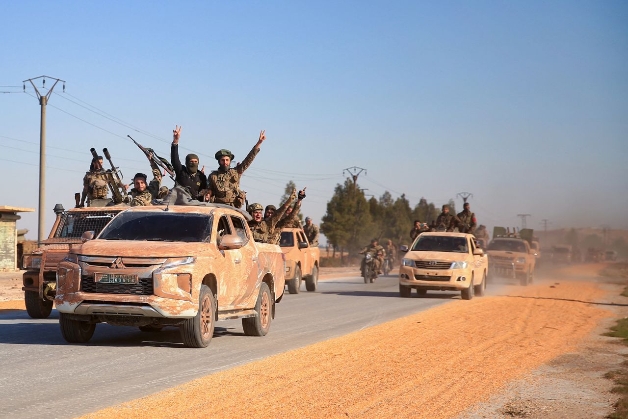 Anti-government fighters ride military vehicles as they drive along a road in the eastern part of Aleppo province on December 1.