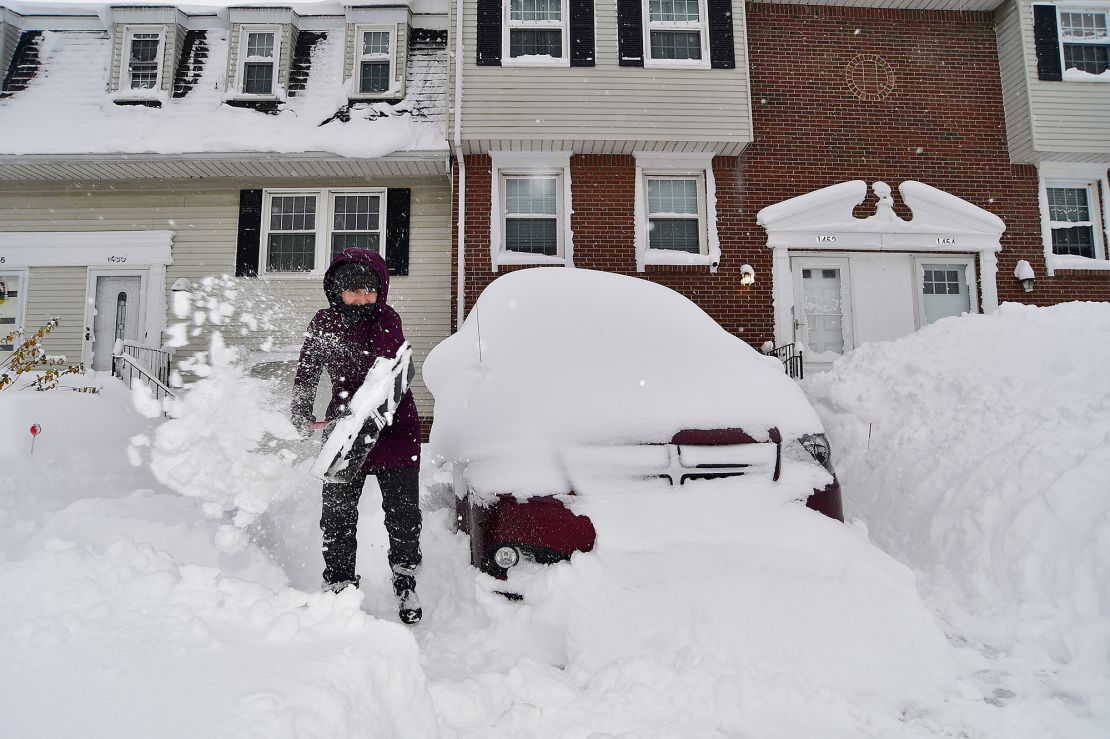 Suzanne Krueger begins the task of removing nearly two feet of lake-effect snow from her home in Derby, New York, on Sunday.