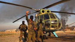 Anti-regime fighters pose for a picture with an army helicopter on the tarmac at the Nayrab military airport in the northern Syrian city of Aleppo on December 2, 2024. Islamist-led rebels on November 30, seized most of Aleppo, along with its airport and dozens of nearby towns, the war monitor Syrian Observatory for Human Rights said. (Photo by AAREF WATAD / AFP) (Photo by AAREF WATAD/AFP via Getty Images)