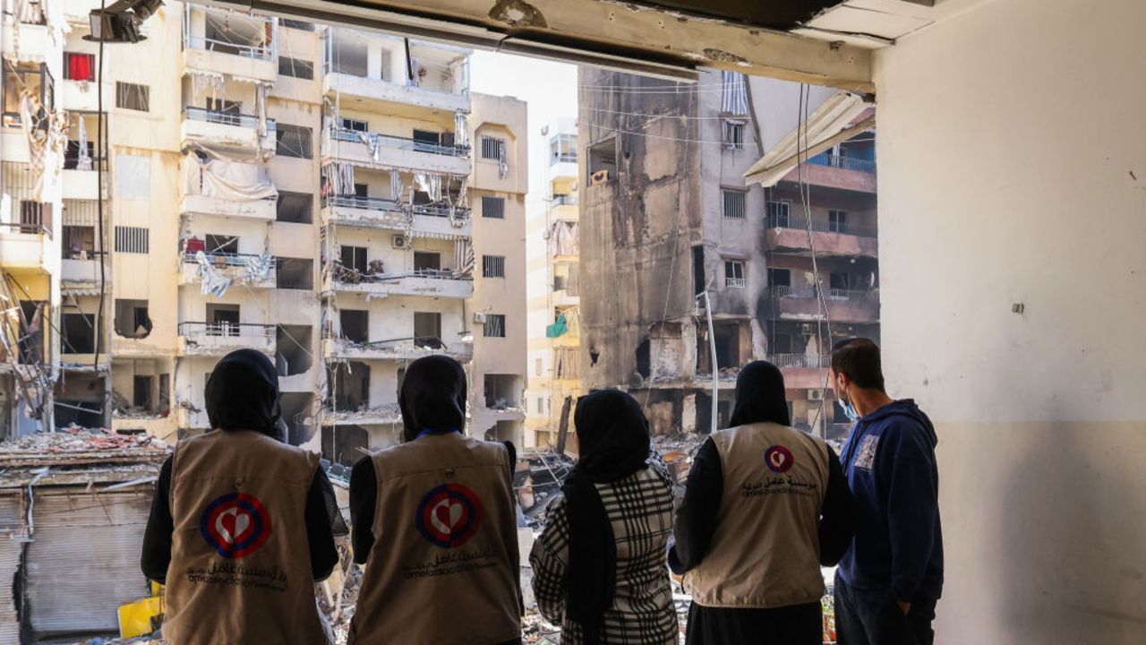 TOPSHOT - Staff members of the Amel Association Amel Association, a Lebanese non-governmental organisation, look out their damaged branch at buildings destroyed or damaged in an Israeli strike, in Beirut's southern suburbs Hay el-Sellom neighbourhood on December 2, 2024. (Photo by Anwar AMRO / AFP) (Photo by ANWAR AMRO/AFP via Getty Images)