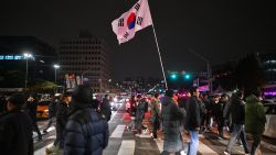 TOPSHOT - A man holds the South Korea flag outside the National Assembly in Seoul on December 4, 2024, after President Yoon Suk Yeol declared emergency martial law. South Korea's President Yoon Suk Yeol on December 3 declared emergency martial law, saying the step was necessary to protect the country from "communist forces" amid parliamentary wrangling over a budget bill. (Photo by ANTHONY WALLACE / AFP) (Photo by ANTHONY WALLACE/AFP via Getty Images)