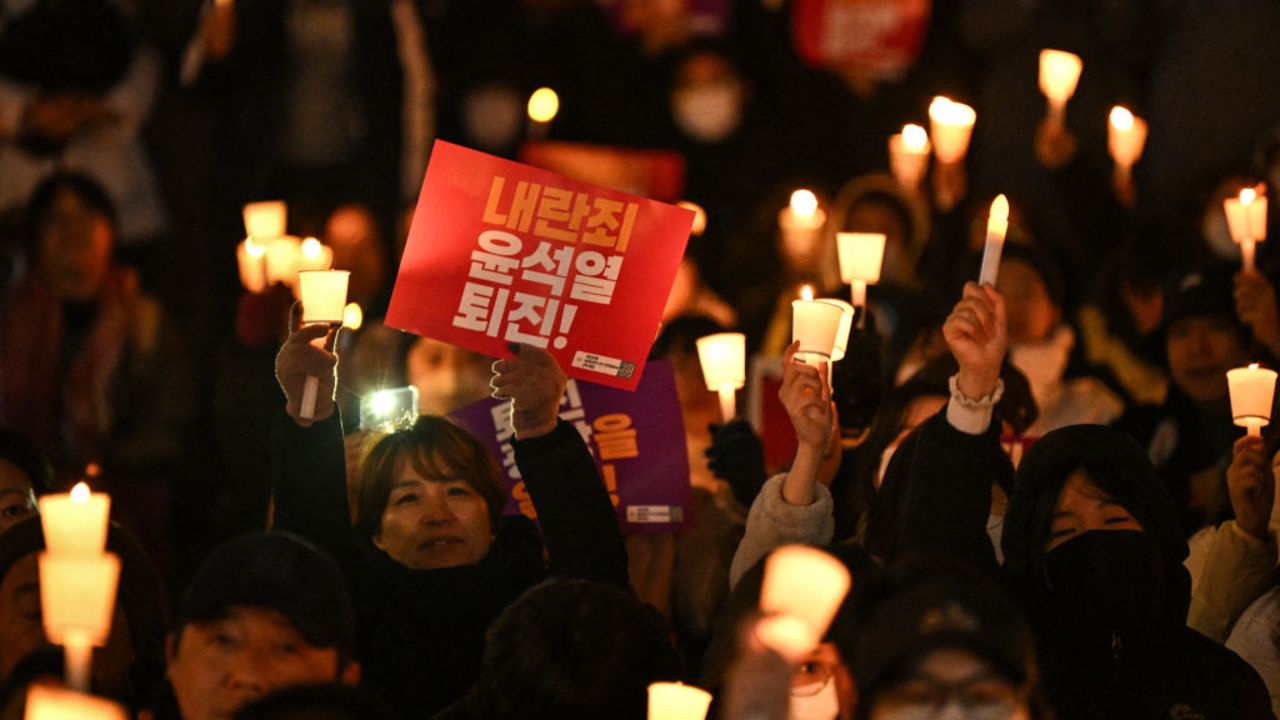 A woman holds a sign that reads "Insurrection Yoon Suk Yeol step down!" during a candlelight vigil to protest against South Korea President Yoon in Seoul on December 4, 2024. South Korea's opposition moved to impeach Yoon on December 4 after his extraordinary but short-lived imposition of martial law that brought thousands of protesters to the streets. (Photo by Philip FONG / AFP) (Photo by PHILIP FONG/AFP via Getty Images)