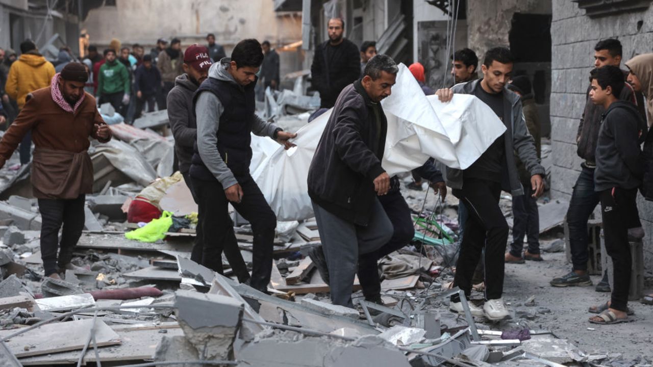 Palestinian men carry the body of a victim of an Israeli strike in Gaza City's Daraj neighbourhood, on December 5, 2024, amid the ongoing war between Israel and Hamas militants. (Photo by Omar AL-QATTAA / AFP) (Photo by OMAR AL-QATTAA/AFP via Getty Images)