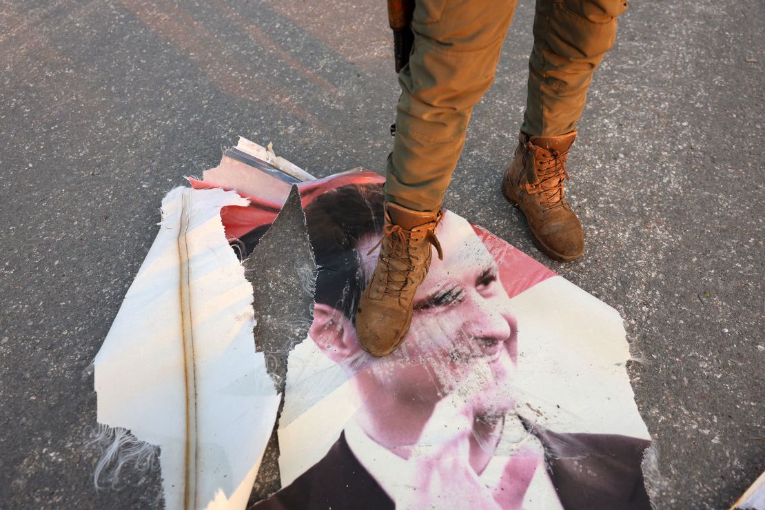 An opposition fighter steps on a torn-up portrait of Syria's President Bashar al-Assad in Hama, a day after rebels captured the city on December 6, 2024.