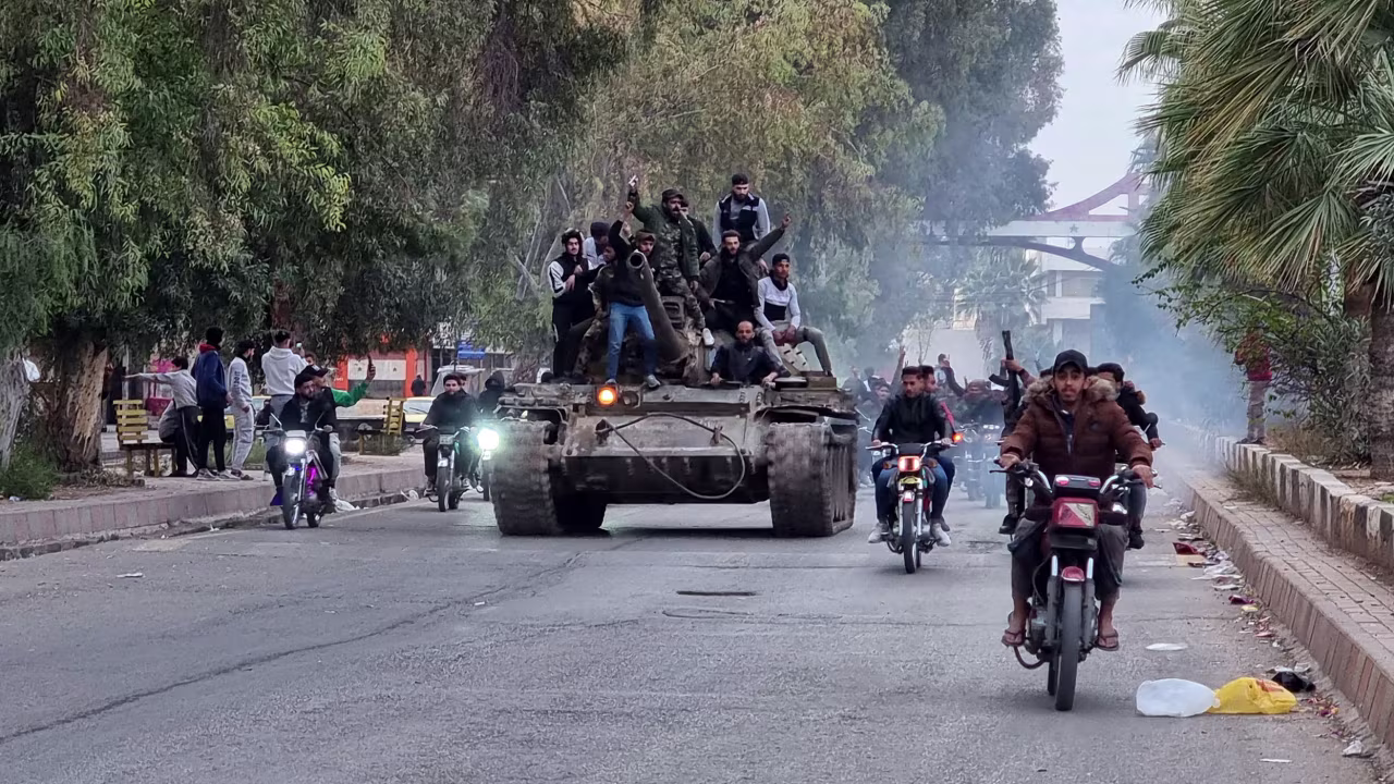 People ride a tank in the southern Syrian city of Daraa on December 7 after the collapse of government forces.
