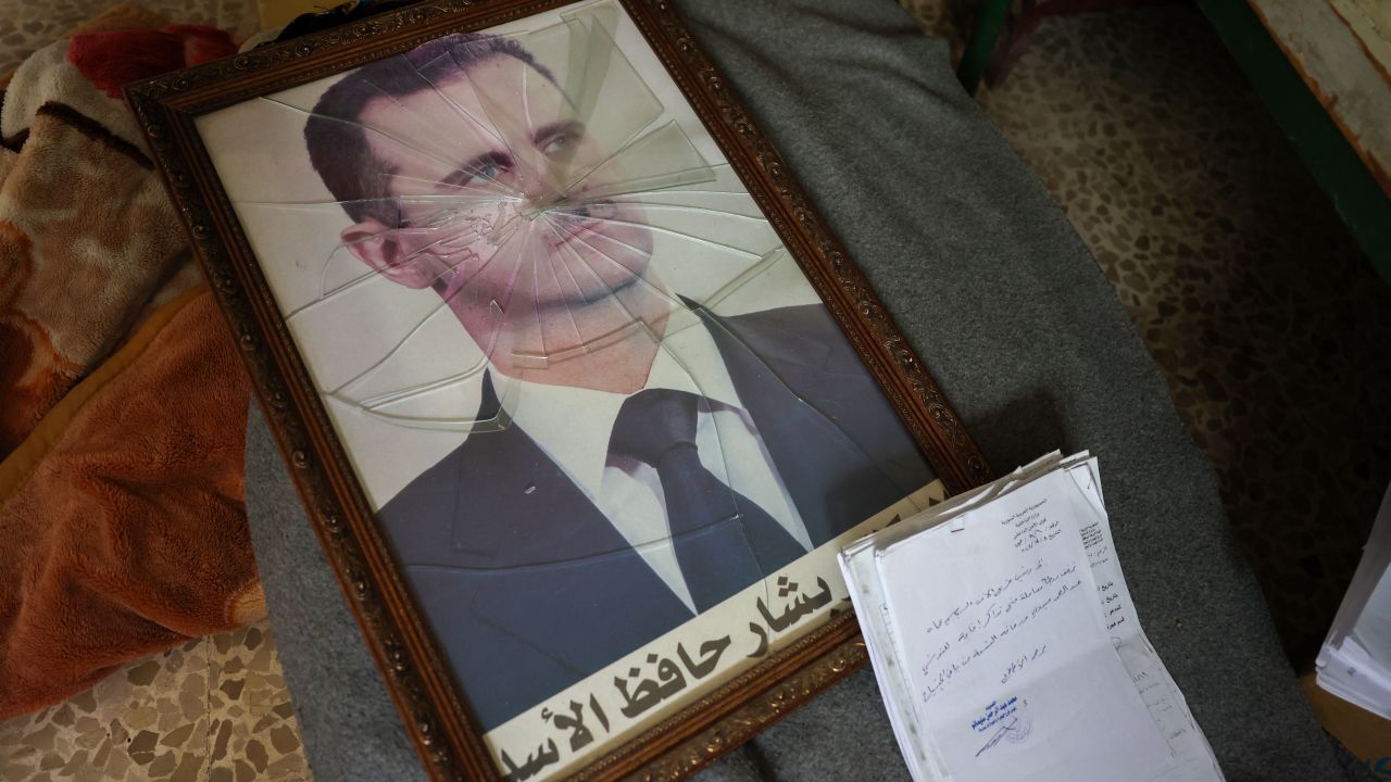 TOPSHOT - A portrait of Syrian President Bashar al-Assad is pictured with its frame broken, in a Syrian regime's Political Security Branch facility on the outskirts of the central city of Hama, following the capture of the area by anti-government forces, on December 7, 2024. Syria's embattled government said on December 7 it was setting up a ring of steel around Damascus, state media reported, as rebels on a lightning advance said they were bearing down on the city. The leader of Hayat Tahrir al-Sham (HTS), the Islamist group which has headed the assault, told fighters to prepare to take Damascus, just over a week into a renewed offensive in the long dormant conflict. (Photo by OMAR HAJ KADOUR / AFP) (Photo by OMAR HAJ KADOUR/AFP via Getty Images)