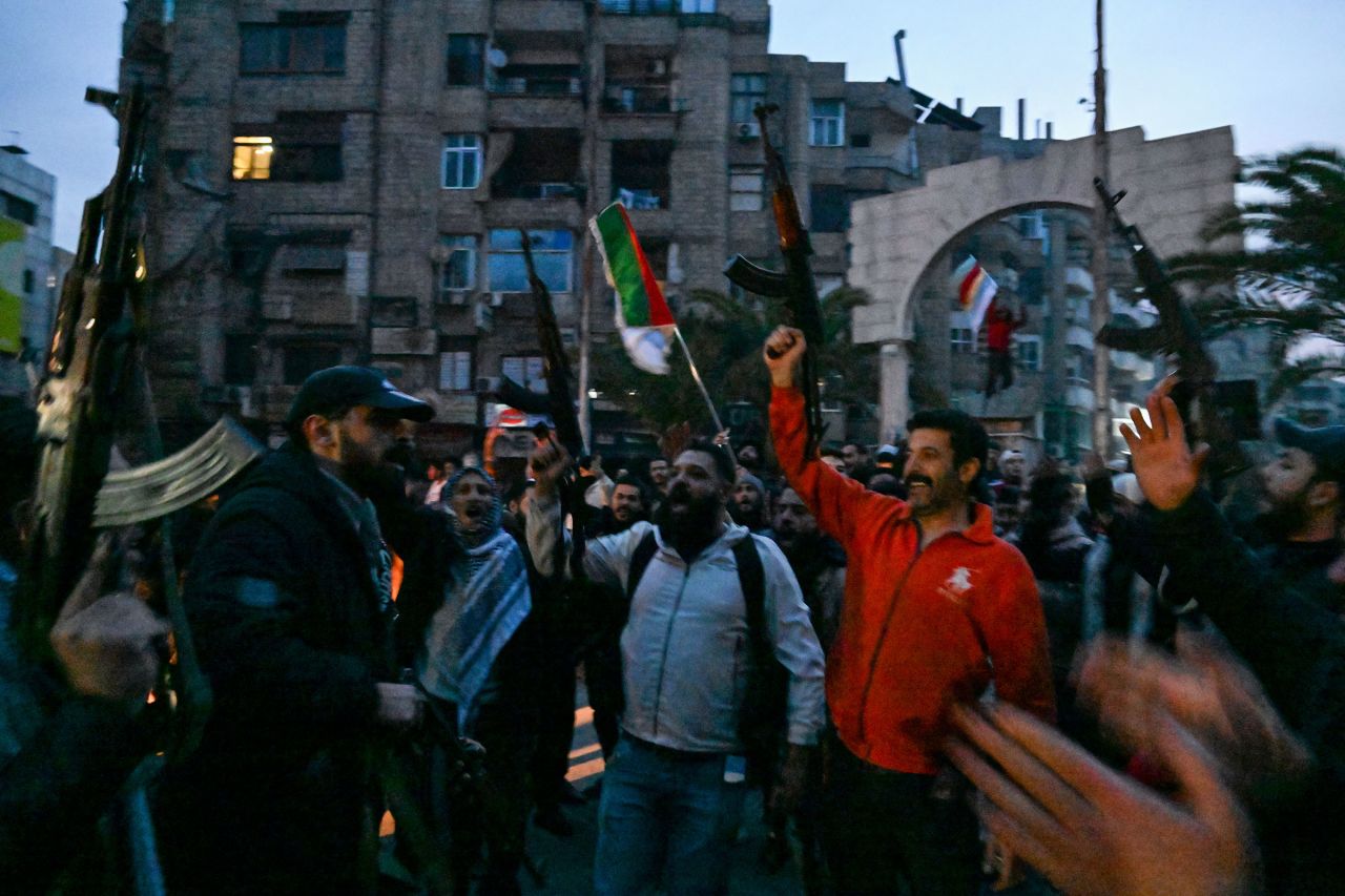 Local residents cheer as the gather on a street in the Damascus suburb of Jaramana, in Syria, on December 8.