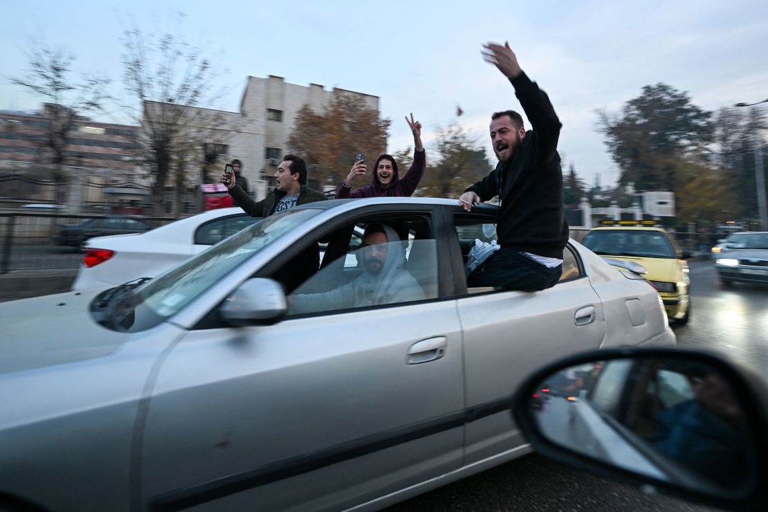 People cheer while riding in a car along a street in Damascus, Syria, on December 8.