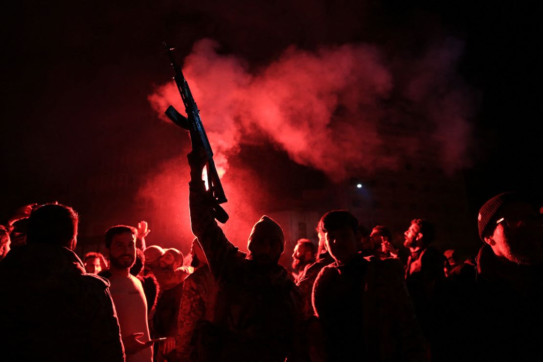 Rebel forces shoot in the air as they celebrate in the central Syrian city of Homs early on December 8