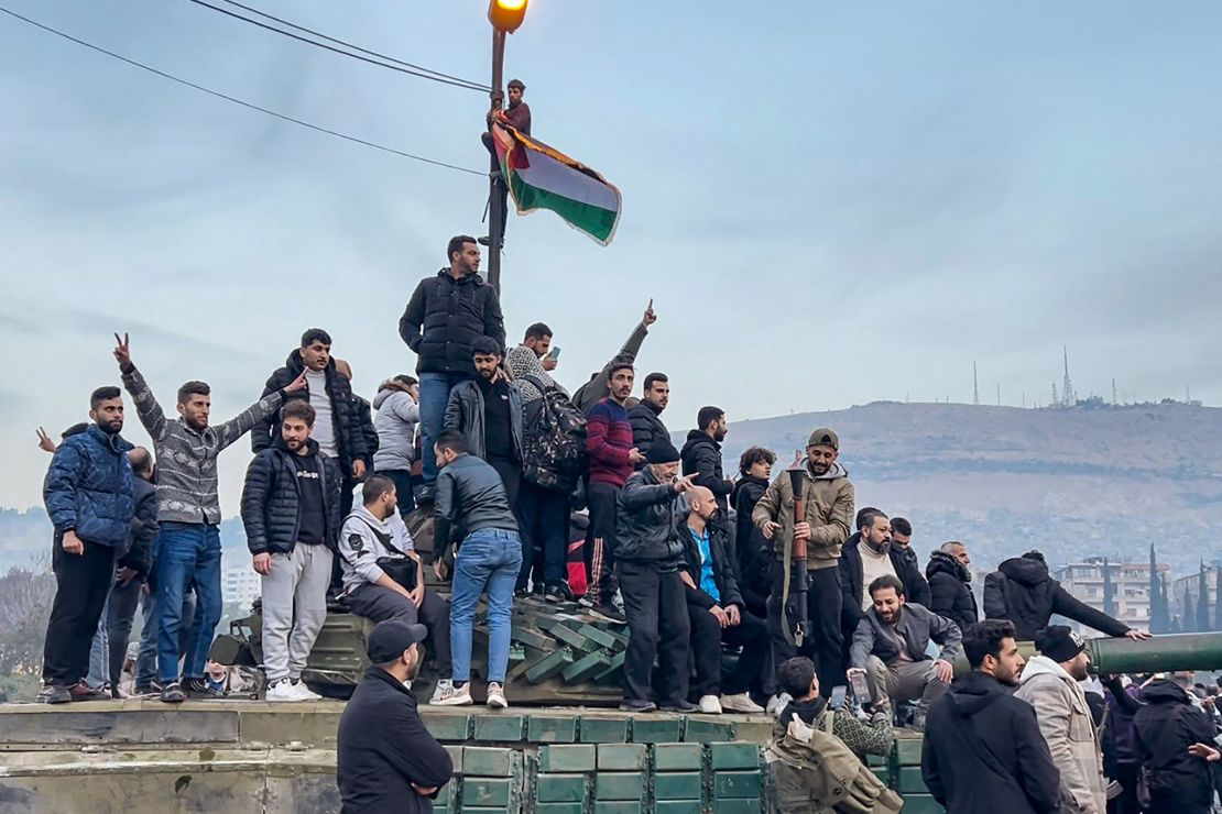 This screen grab taken from AFPTV shows people sitting on a tank as they gather at Umayyad Square in Damascus, Syria on December 8, 2024.