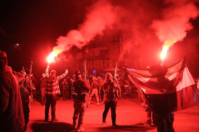 Rebel forces shoot in the air as they celebrate in the central Syrian city of Homs early on December 8.