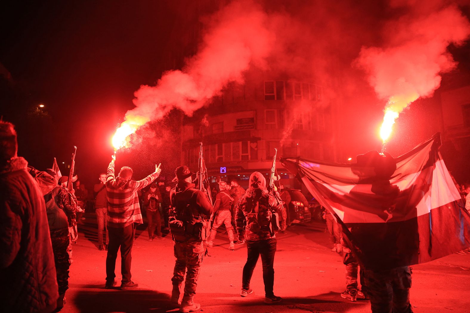 Rebel forces shoot in the air as they celebrate in the central Syrian city of Homs early on December 8.