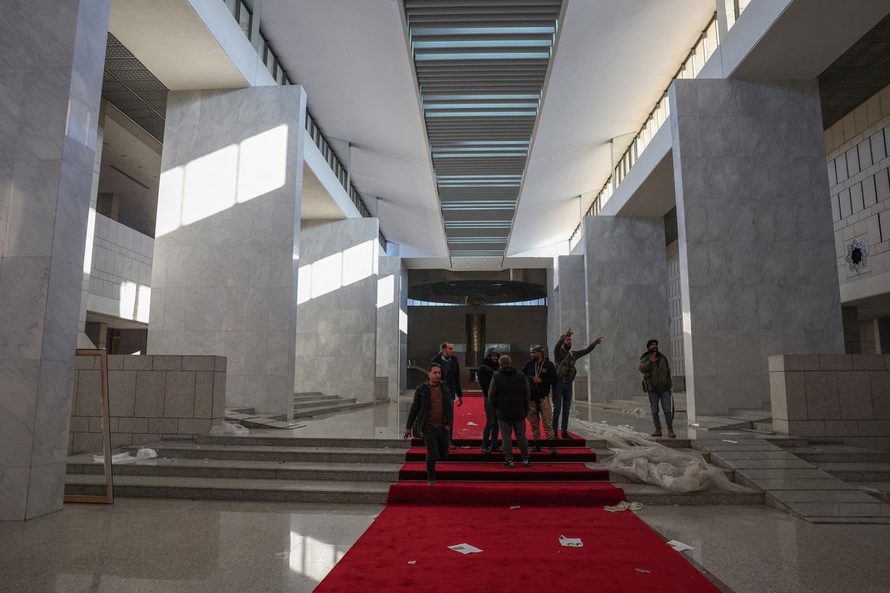 Rebel fighters walk in the Syrian presidential palace in Damascus on December 8.