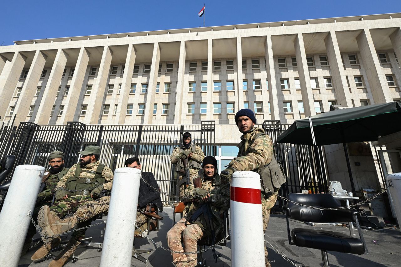 Anti government forces stand guard in front of Syria's Central Bank in Damascus, on December 9.