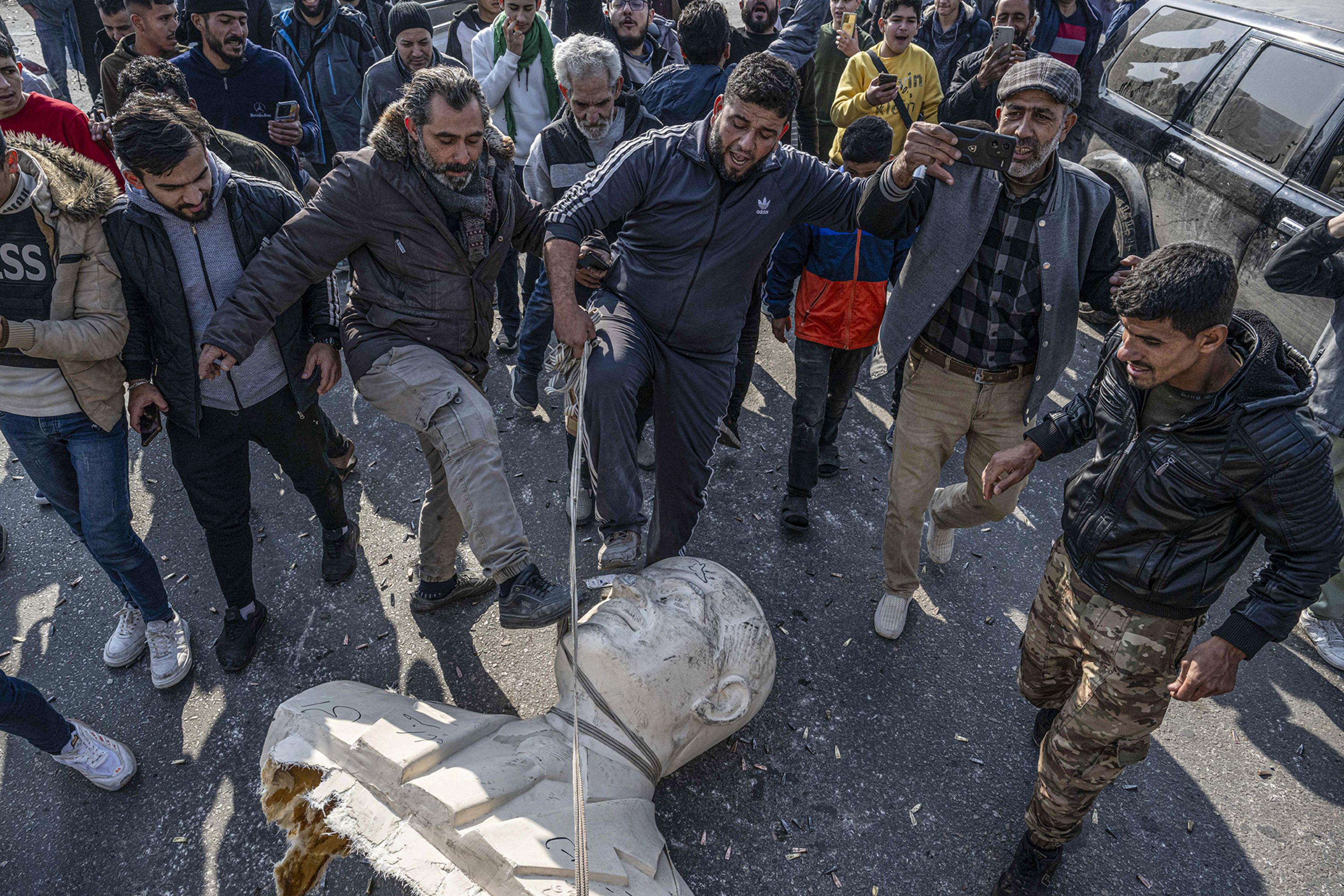 Citizens in Syria take down statues of Hafez al-Assad, the father of Bashar al-Assad, in Damascus, on December 9.