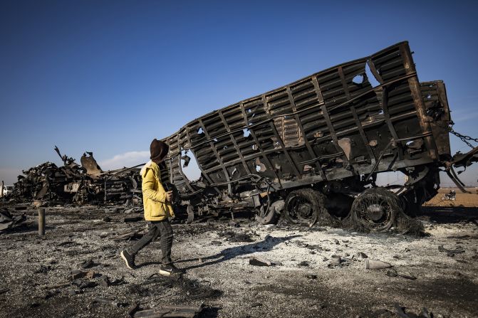 A boy walks past a destroyed military vehicle at the site of an Israeli airstrike in Qamishli, Syria, on December 10.