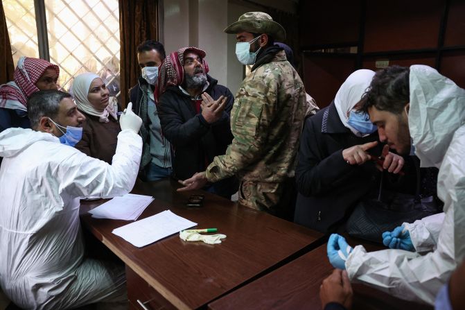 People looking for relatives talk to sanitary workers and an anti government fighter at the morgue of a hospital in Damascus on December 10, a day after bodies bearing signs of torture were found.