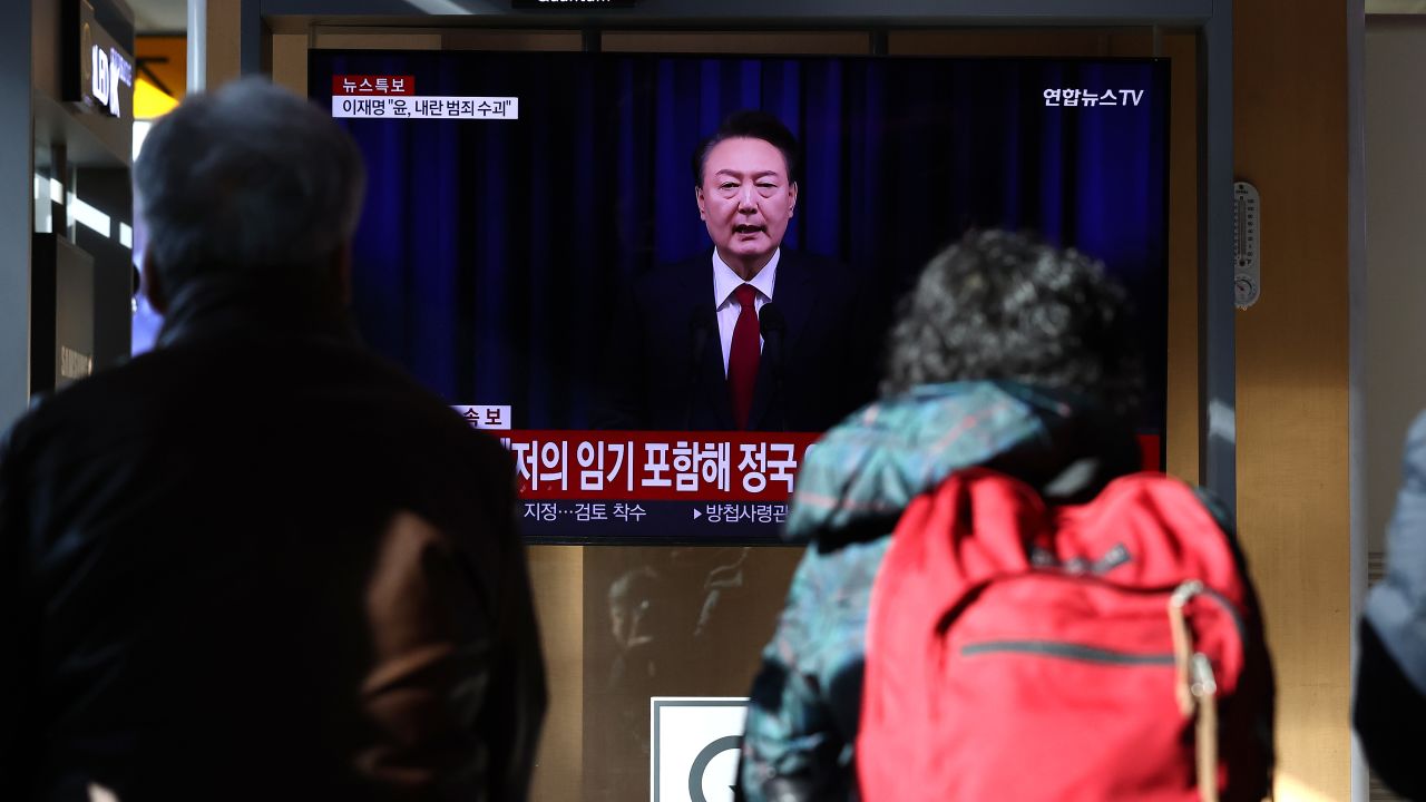 SEOUL, SOUTH KOREA - DECEMBER 07: A screens shows footage of South Korean President Yoon Suk Yeol delivering an address to the nation at Seoul station on December 07, 2024 in Seoul, South Korea. South Korea is facing significant political turmoil after President Yoon Suk-yeol declared emergency martial law, accusing opposition parties of destabilizing governance and sympathizing with North Korea. His controversial move, since rescinded after a 190-0 vote by lawmakers condemning the move, has sparked widespread criticism, calls for Yoon's resignation, and raised concerns about the implications for democracy in the country. (Photo by Chung Sung-Jun/Getty Images)