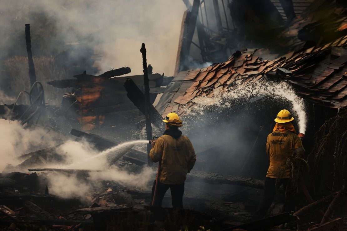 Firefighters work at a burned home in Malibu on Tuesday.