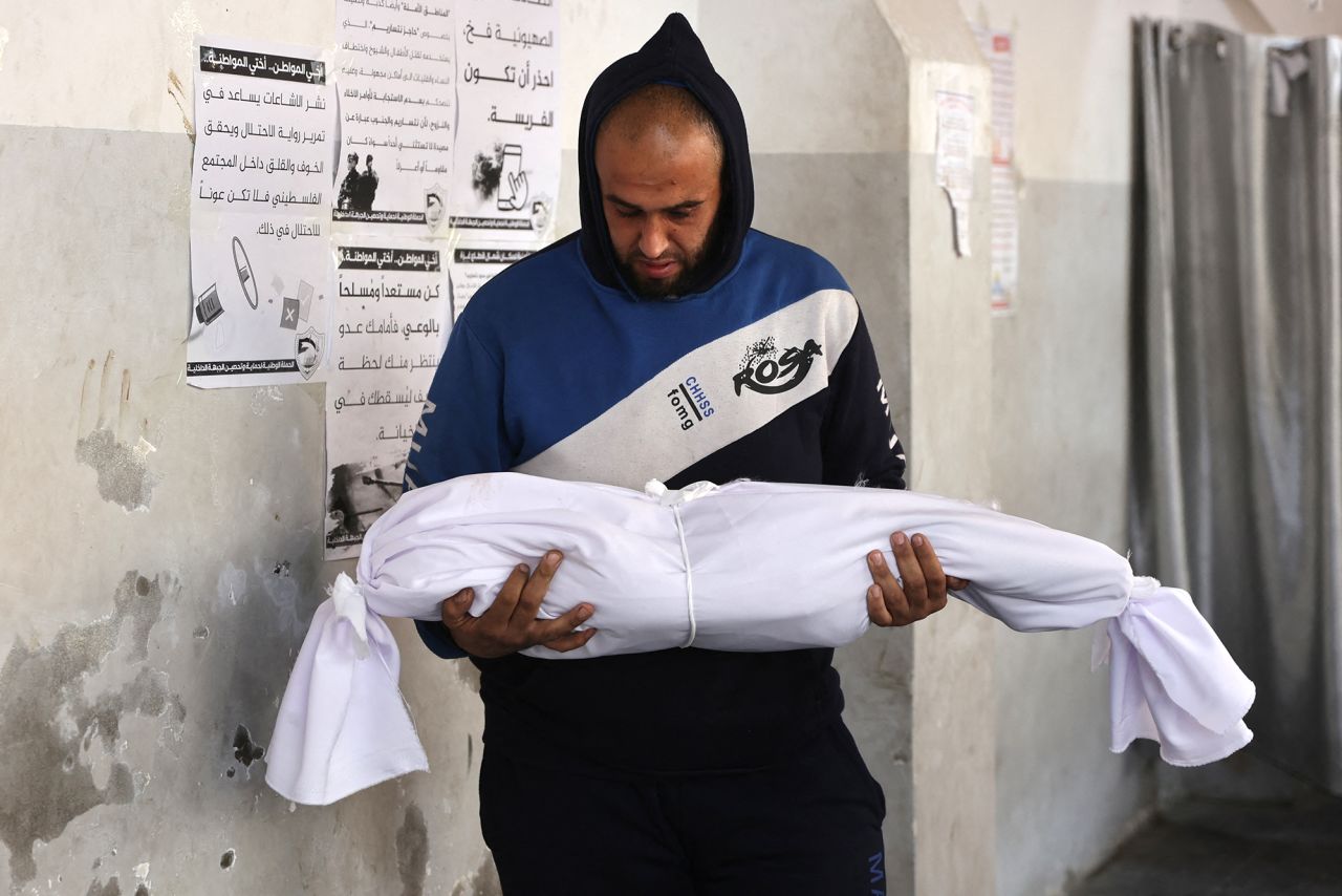 A Palestinian man carries the body of a child killed in overnight Israeli air strikes in Gaza, on December 12.