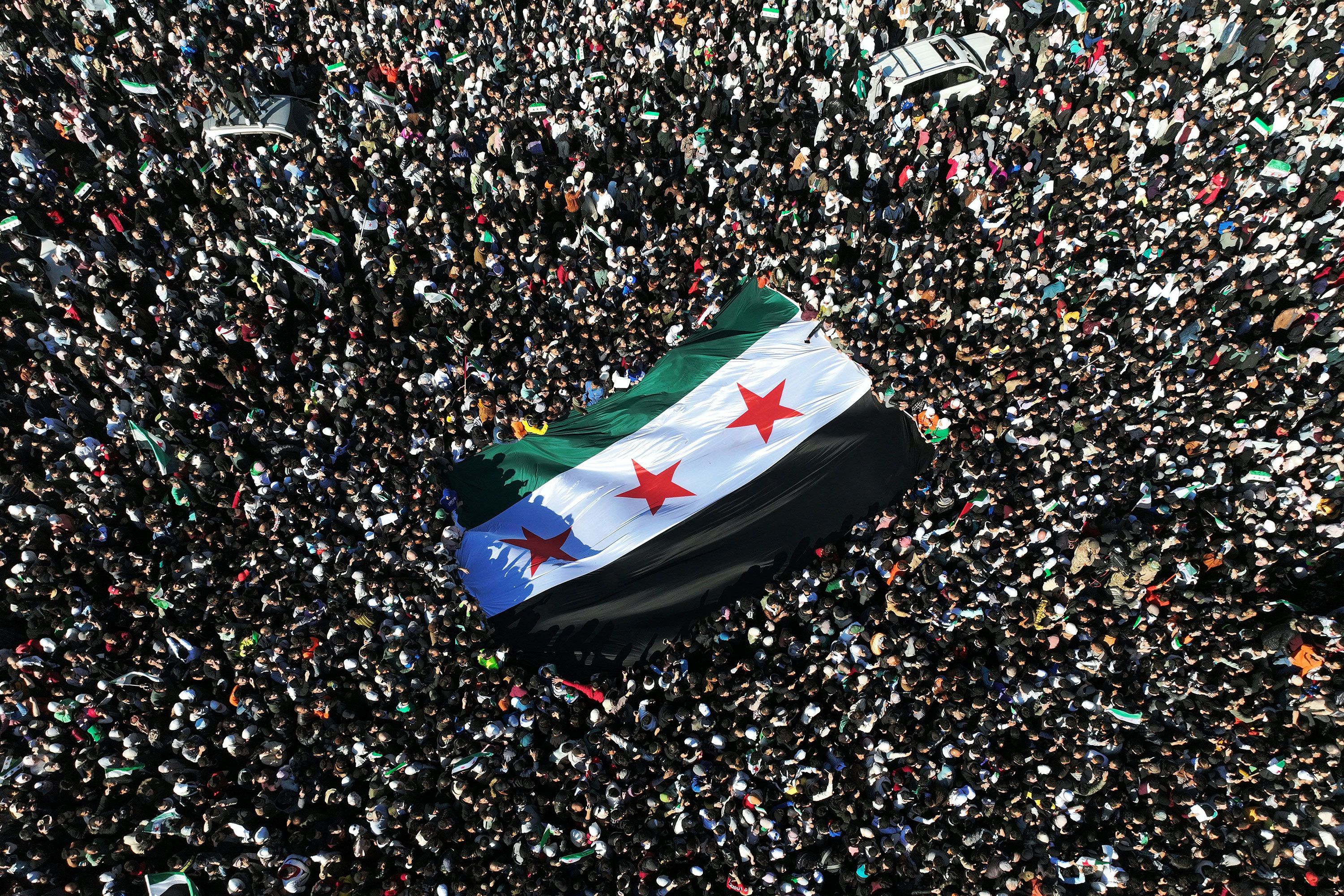 Syrians raise a giant flag as they celebrate the fall of the Assad regime in the central Umayyad Square in Damascus, Syria, on December 13.