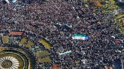 DAMASCUS, SYRIA - DECEMBER 13: In this aerial view, people unfurl a large Syrian flag as they celebrate in Umayyad Square after Friday Prayers on December 13, 2024 in Damascus, Syria. Last week, rebel forces in Syria retook the capital from longtime ruler Bashar al-Assad, who fled the country for Moscow. The fall of the Assad regime marks a new chapter for Syria, which has been mired in a multi-party civil war since 2011, sparked by the Arab Spring uprisings. (Photo by Ali Haj Suleiman/Getty Images)