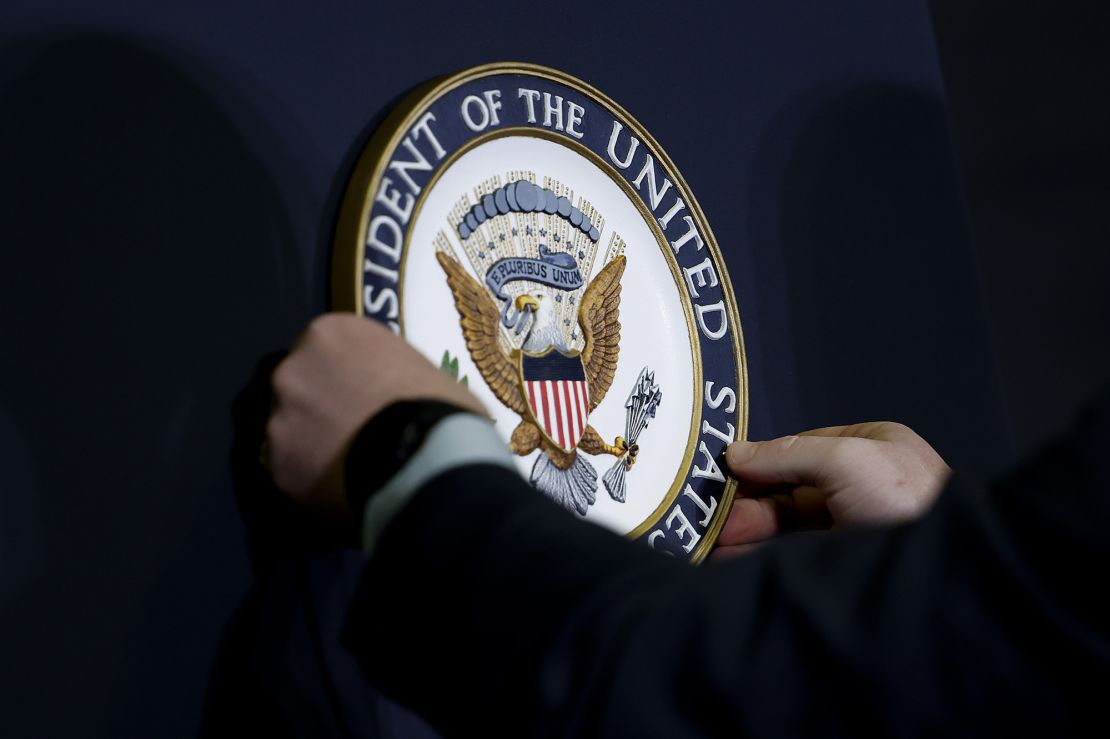 A staff member places the seal at the podium for Vice President Kamala Harris at the 2024 Tribal Nations Summit at the Interior Department on December 9, 2024, in Washington.