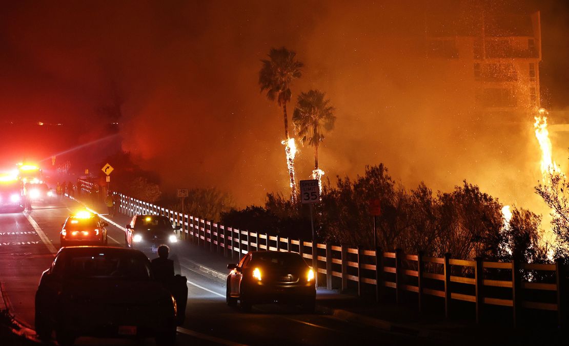 Firefighters work as the Franklin Fire burns near a building on Tuesday in Malibu, California.