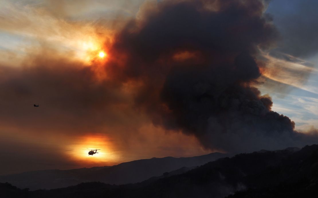 The silhouette of a firefighting helicopter is silhouetted against the Pacific Ocean as the Franklin Fire continues to burn near Malibu, California, on Tuesday.