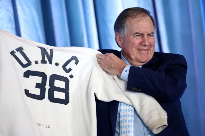 Belichick holds up one of his father's old sweatshirts as he is <a href="index.php?page=&url=https%3A%2F%2Fwww.cnn.com%2F2024%2F12%2F12%2Fsport%2Fbill-belichick-unveiled-head-coach-north-carolina-spt%2Findex.html">unveiled as the new head coach at the University of North Carolina</a> in December 2024. Belichick's father, Steve, coached at UNC in the 1950s.