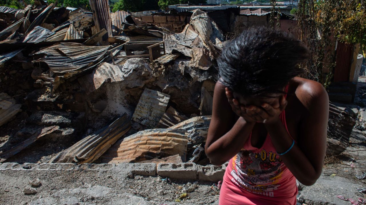 TOPSHOT - A woman cries outside her house after armed gangs set it on fire in the Post Marchand neighborhood of Port-au-Prince on December 17, 2024. (Photo by Clarens SIFFROY / AFP) (Photo by CLARENS SIFFROY/AFP via Getty Images)