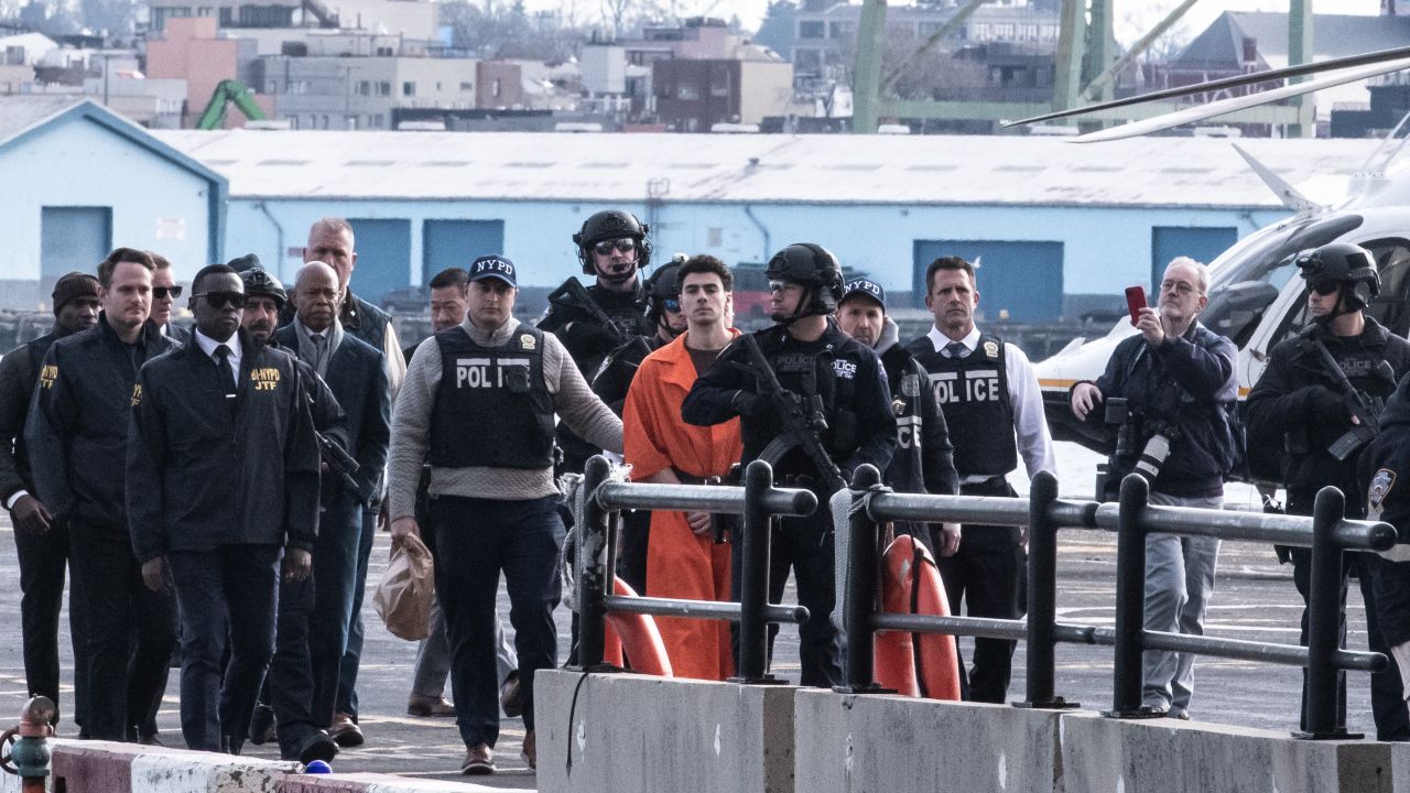 NEW YORK, NEW YORK - DECEMBER 19: Luigi Mangione, suspect in the killing of UnitedHealthcare CEO Brian Thompson in New York City, arrives at a heliport with members of the NYPD on December 19, 2024 in New York City. The 26-year-old was arrested in Pennsylvania on December 9 after being spotted at a McDonald's in Altoona amid a national manhunt. Mangione also appeared in a Pennsylvania court on forgery and firearms charges today, where he waived extradition to New York after being indicted on 11 charges including first-degree murder in furtherance of terrorism. (Photo by Stephanie Keith/Getty Images)