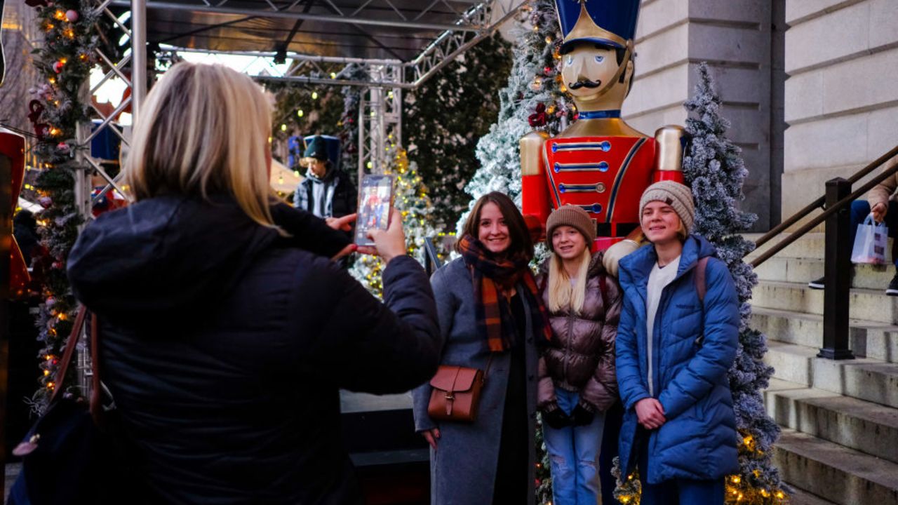 People take photos at a Christmas market in downtown Washington, DC, December 21, 2024. (Photo by RICHARD PIERRIN / AFP) (Photo by RICHARD PIERRIN/AFP via Getty Images)