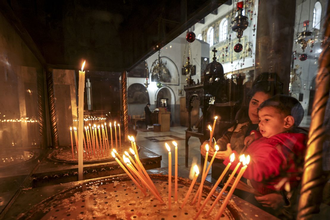 A woman and child light candles at the Greek Basilica in the Nativity Church Complex in Bethlehem, in the occupied West Bank, on December 22, 2024.