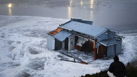People look at the collapsed pier at the Santa Cruz Wharf in Santa Cruz, California, on December 23, 2024. A pier collapsed into the ocean and floated away off the US state of California on Monday, weather authorities said, as the region was pounded by a powerful storm. Lifeguards rescued two people after the structure in Santa Cruz broke free, firefighters said, while a third person managed to get themselves out of trouble. (Photo by Daniel Dreifuss / AFP)