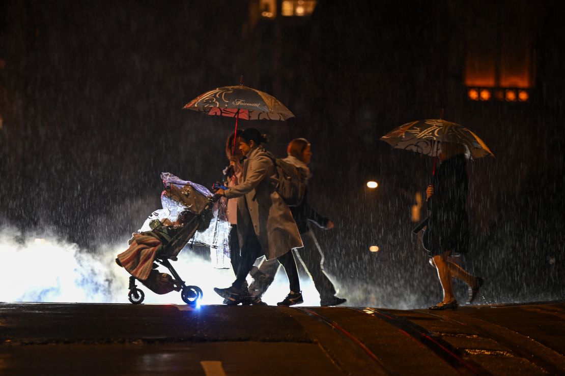 People are seen at a crosswalk on California and Mason street during heavy rain in San Francisco, California, United States on December 26, 2024.